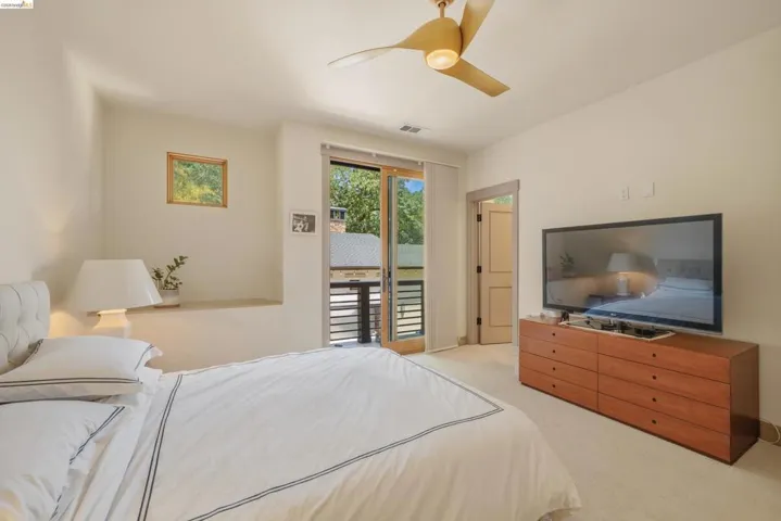 Bright interior space featuring a light wood-finish ceiling fan, a built-in wall shelf, and a square window with wood trim