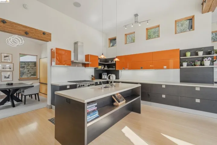 Modern kitchen featuring light wood-finish flooring and a high vaulted ceiling with exposed wood beams