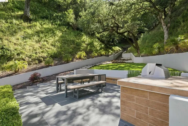 Outdoor entertaining area with a built-in barbecue station, tile-finish countertop, and wood-look paneling
