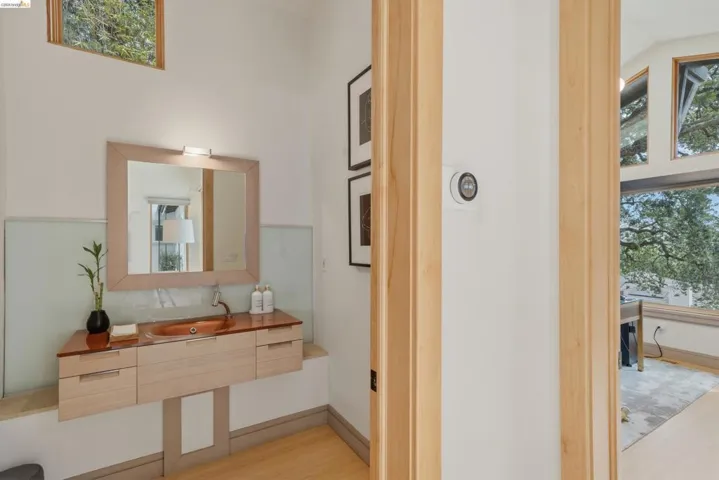 Floating vanity with a built-in vessel sink and a wall-mounted faucet, complemented by a framed mirror with integrated lighting