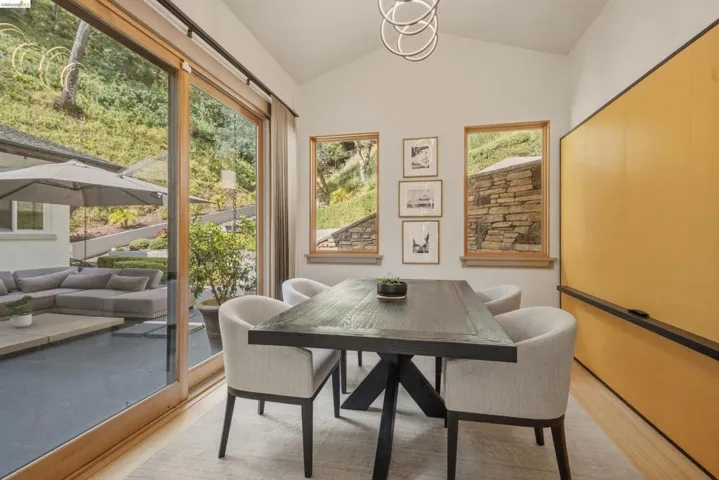Vaulted ceiling dining area featuring wood-finish flooring and a large sliding glass door