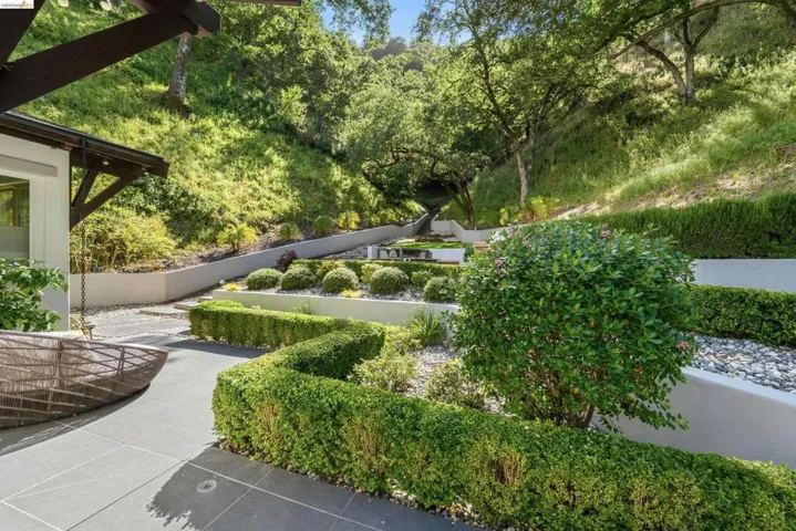 Terraced landscape design featuring manicured shrubbery, gravel accents, and mature trees
