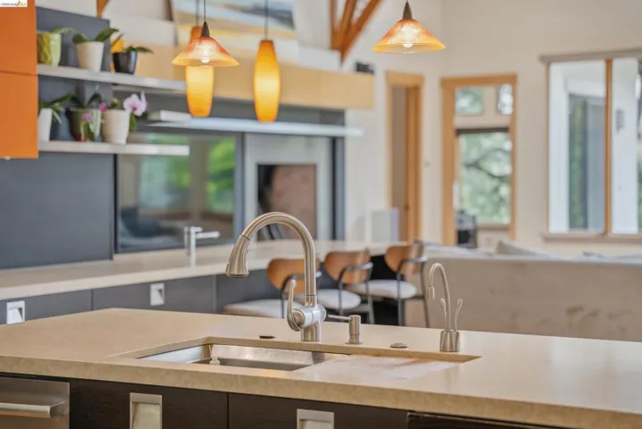 Contemporary kitchen island with an undermount sink, gooseneck faucet, and light-toned countertop