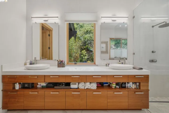 Dual vessel sinks set into a white countertop, framed by modern rectangular mirrors with integrated lighting