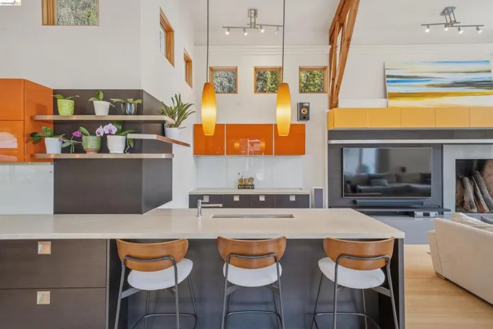 Open-concept kitchen featuring an island with built-in seating, quartz countertops, modern pendant lighting, and warm wood-finish flooring