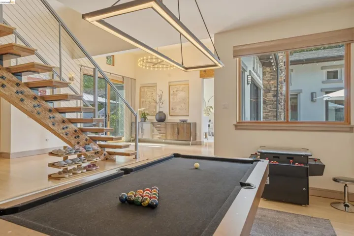 Open-tread staircase with cable railing, light wood-finish flooring, and a contemporary linear chandelier