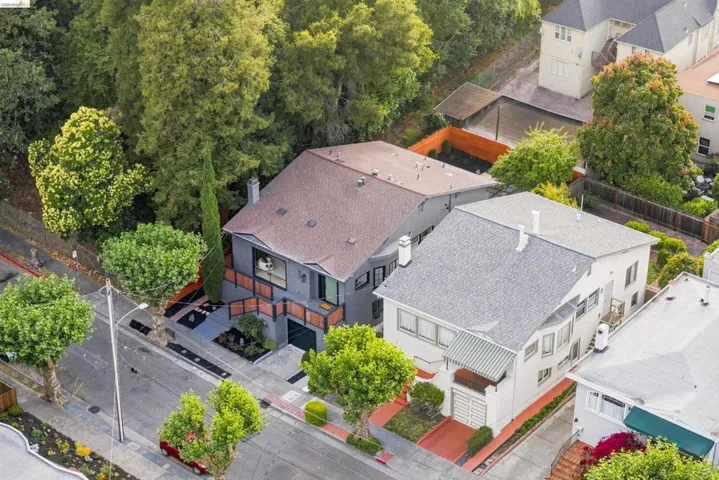 Contemporary multi-level residence featuring a dark gray exterior, prominent brown shingle roofing, and a wooden fence with horizontal slats