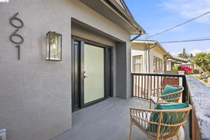 Private balcony featuring a textured stucco exterior, contemporary wall sconce, privacy glass door, and dark railings