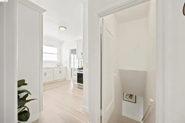 Kitchen entry with wood-finish flooring, recessed lighting, white cabinetry, and a window above the sink