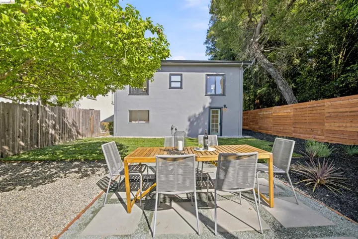 Expansive backyard featuring a gray stucco exterior, a large lawn area, and a horizontal wood privacy fence
