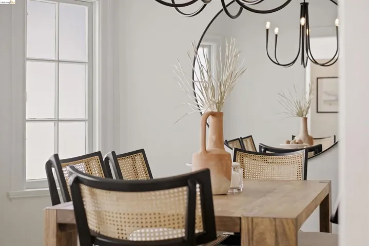 Dining area featuring a substantial wood-finish table, a multi-pane window, and a contemporary black chandelier