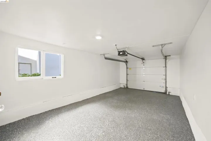 Spacious garage featuring a durable speckled epoxy floor, white walls, and a window for natural light
