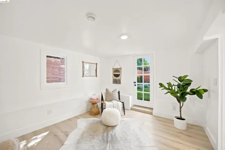 Bright room featuring light wood-finish flooring, white walls, and a white paneled door with windowpanes providing exterior access
