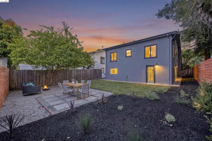 Expansive backyard featuring a paver patio with gravel surround, lush lawn, and mature trees
