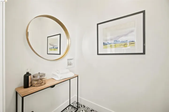Black and white patterned floor tiles complement a light wood-finish console table with a black metal frame