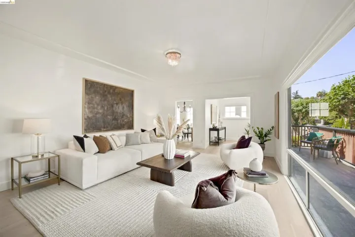 Bright living space featuring light wood-finish flooring, white walls, and a large window offering outdoor access