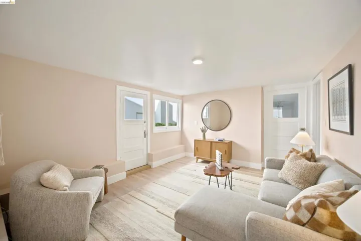 Bright interior space featuring light wood-finish flooring, white baseboards, and pale wall finishes