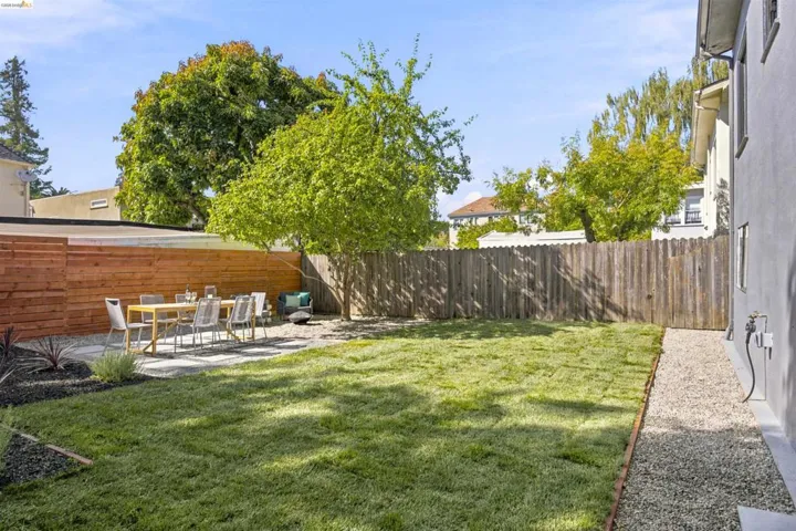 Expansive backyard featuring a green lawn, a dedicated patio with large stepping stones, a modern horizontal wood fence, a traditional vertical wood fence, and mature trees