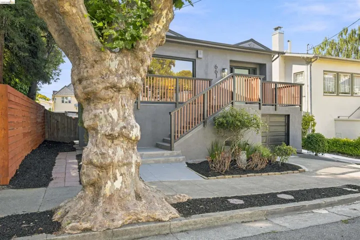 Modern facade with a raised entrance and a prominent deck featuring vertical wood balusters