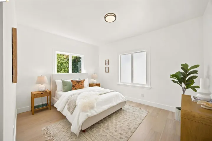 Bedroom featuring light wood-finish flooring, white walls, and two windows