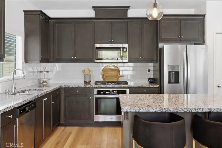 Spacious kitchen with granite countertops, designer backsplash, and stainless-steel appliances