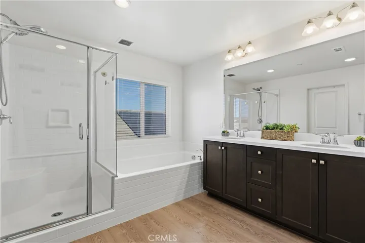 Spa-inspired primary bathroom with dual vanities, a separate soaking tub and walk-in shower, plus a private toilet room