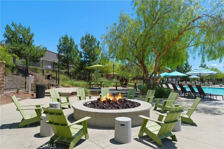 The Oasis firepit offers a relaxing vantage point overlooking the sparkling pool, framed by a beautiful backdrop of mature trees—creating a warm, inviting setting for evening gatherings and sunset views.