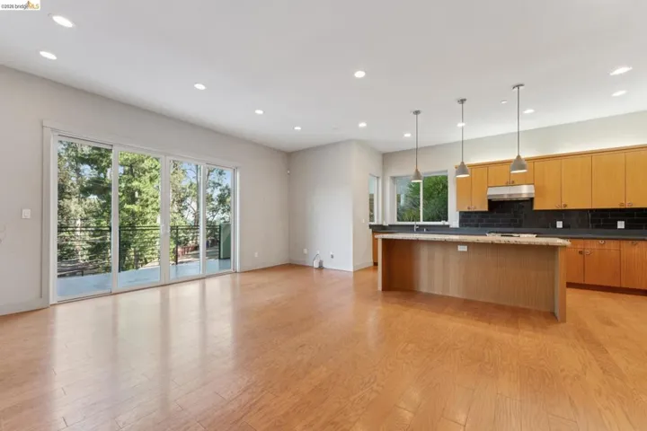 Open-concept living space featuring wood-finish flooring, recessed lighting, and a kitchen island with pendant lighting