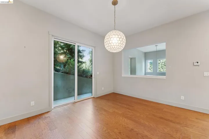 Open-concept room featuring wood-finish flooring, a modern spherical pendant light, and light gray wall paint