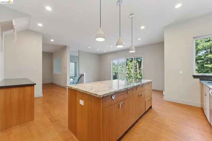 Kitchen island with a light-toned countertop, wood-finish cabinetry, and contemporary pendant lighting