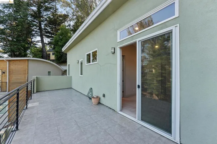 Expansive outdoor patio featuring large format tile flooring, contemporary metal railings, and direct access through a sliding glass door