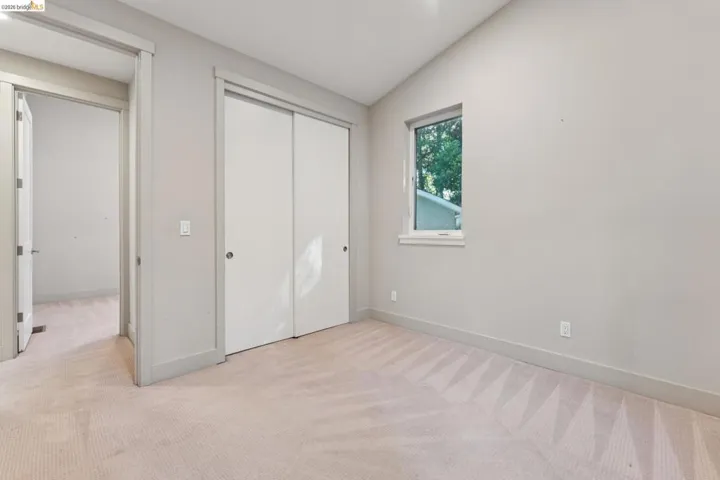 Carpeted room featuring a single window, a double sliding door closet, and a doorway