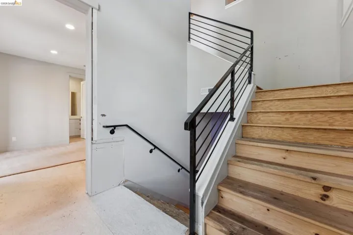 Wood-finish stairs with modern black metal railings and a coordinating handrail