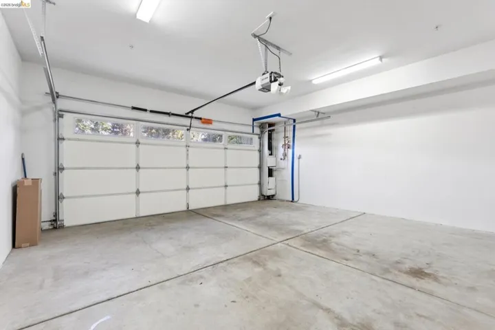 Spacious garage featuring a paneled overhead door with upper transom windows, concrete flooring, and white painted walls