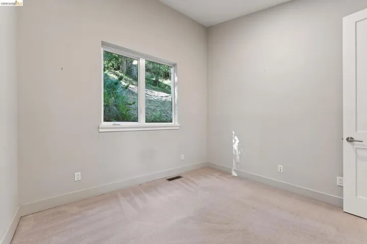 Light-filled interior space featuring a double-paned window, neutral wall paint, light-toned carpeting, and a contemporary door with brushed nickel hardware