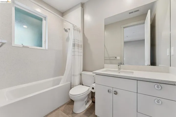 Bathroom featuring a white vanity with integrated sink, coordinating countertop, and a large wall-mounted mirror