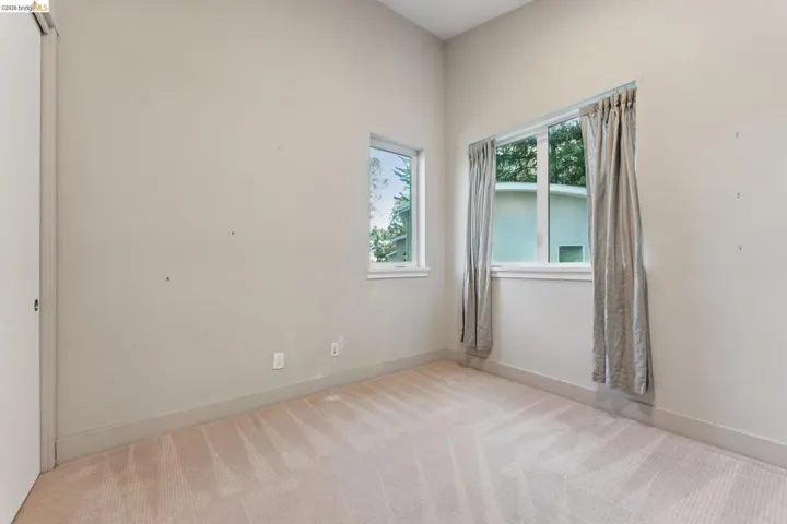 Carpeted room featuring dual windows, neutral wall tones, and a sliding closet door