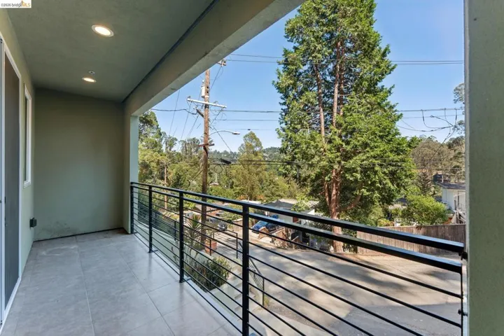Outdoor balcony featuring gray tile flooring, recessed lighting, and a contemporary black metal railing