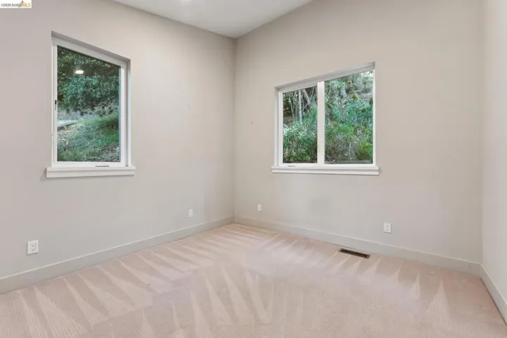 Room featuring two windows, neutral wall tones, and carpeted flooring