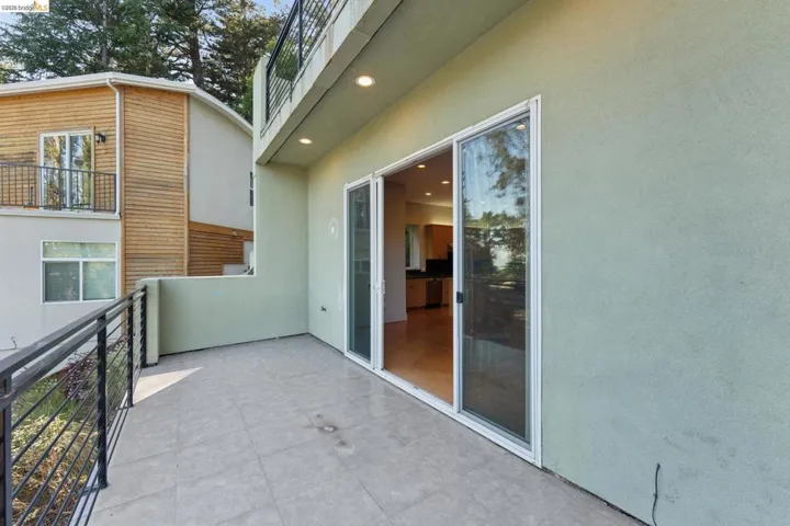 Exterior patio featuring large format tile flooring and a black metal railing