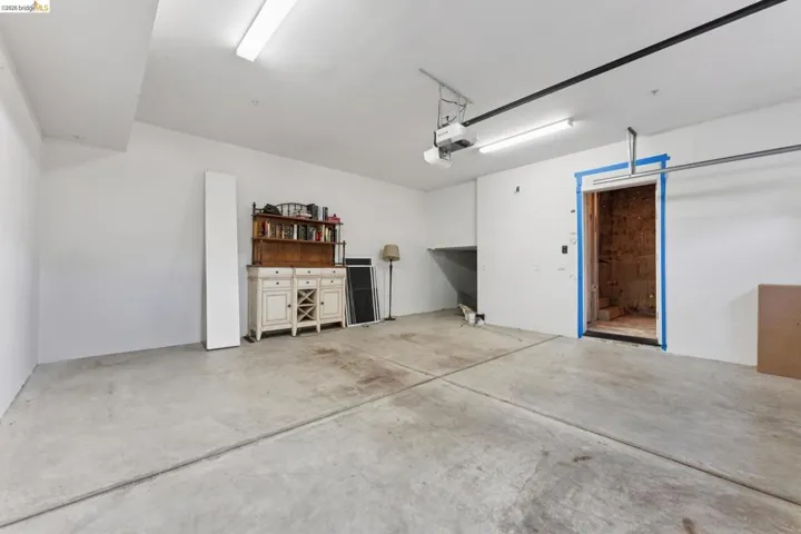 Spacious garage featuring a concrete floor, bright overhead lighting, and white painted walls
