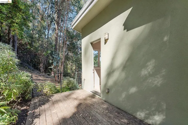 Exterior deck with wood-finish planks, stucco siding, and a wall-mounted light fixture