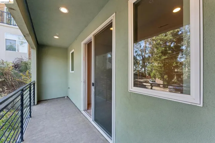 Covered patio with recessed lighting, tile flooring, black metal railing, and sliding glass door access