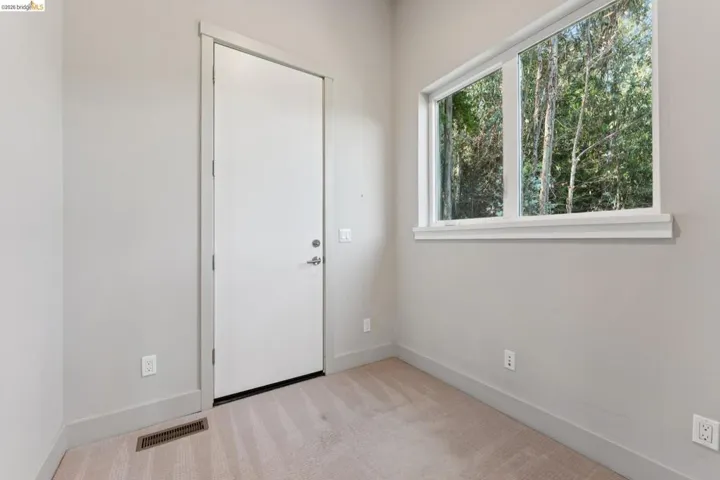 Room featuring light-toned carpeting and a tall white door with brushed nickel hardware