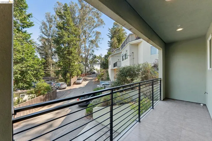 Expansive balcony featuring dark gray tile flooring, a modern horizontal slat railing, recessed lighting, and a stucco exterior