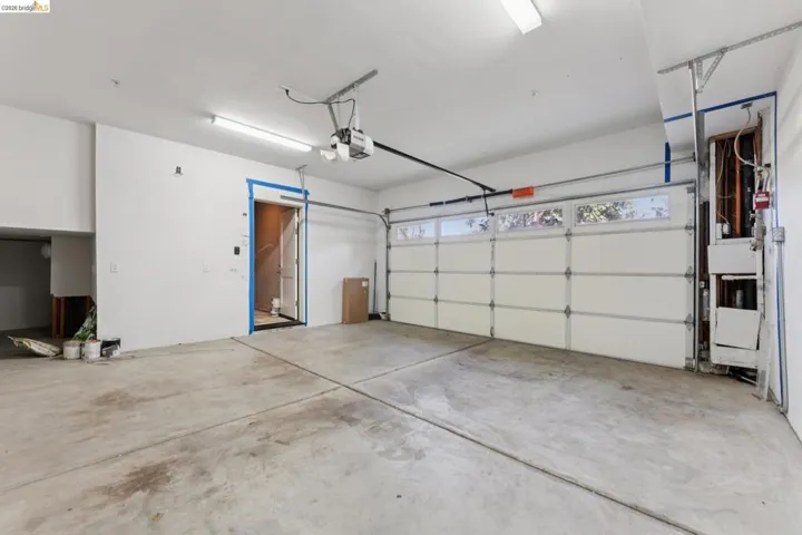 Spacious garage featuring a concrete floor, overhead lighting, and an automatic garage door opener