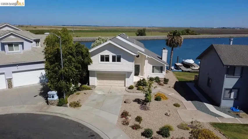 Waterfront property featuring a private boat dock, mature landscaping, and a two-car garage