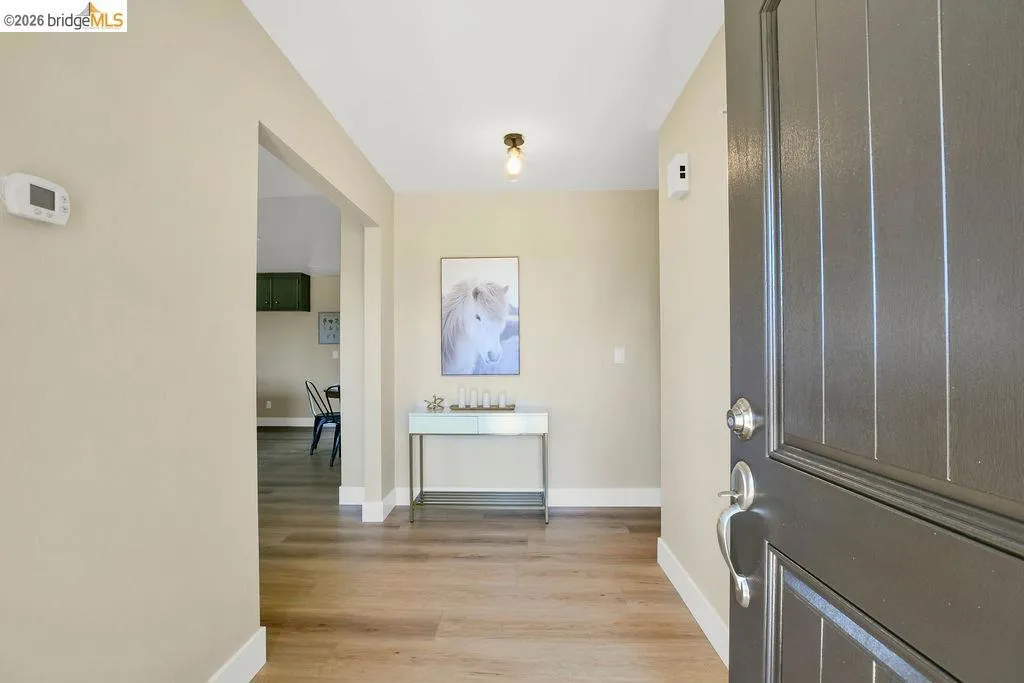 Entryway featuring a dark wood-finish paneled door with polished chrome hardware, wood-finish flooring, and light neutral wall paint