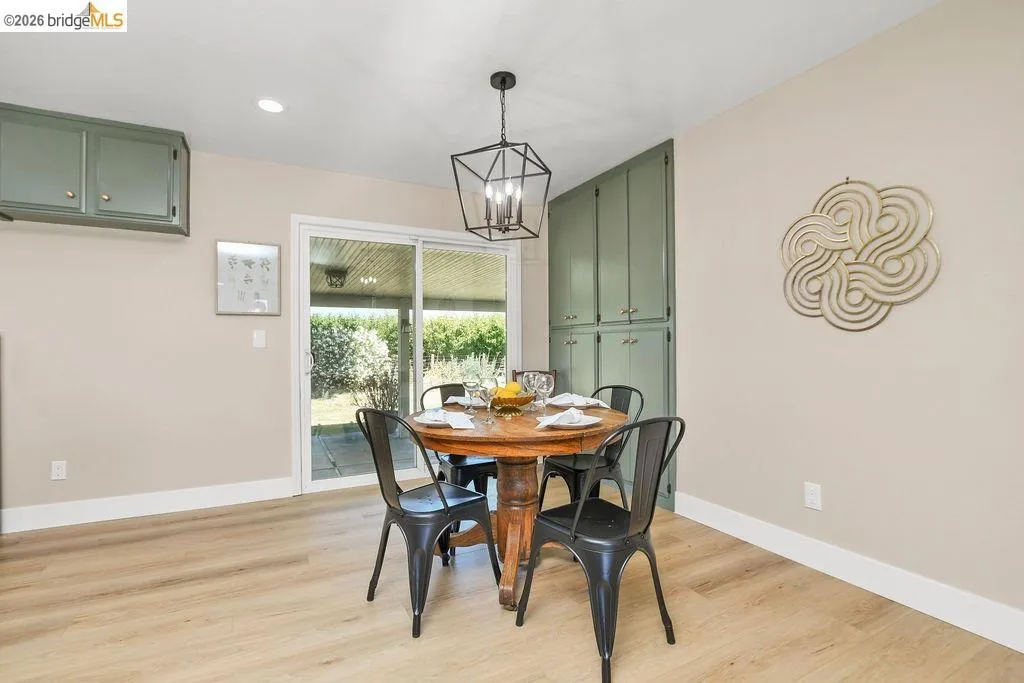 Dining area with wood-finish flooring, recessed lighting, and a contemporary chandelier