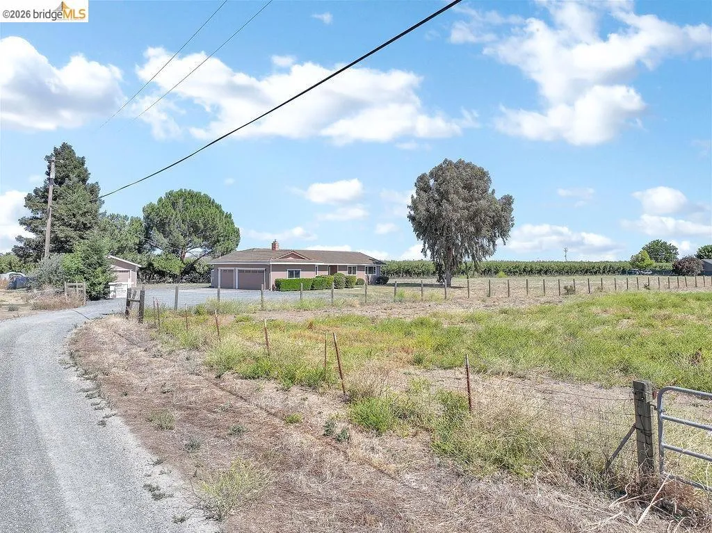 Ranch-style residence featuring a two-car garage, brick chimney, and a gravel driveway